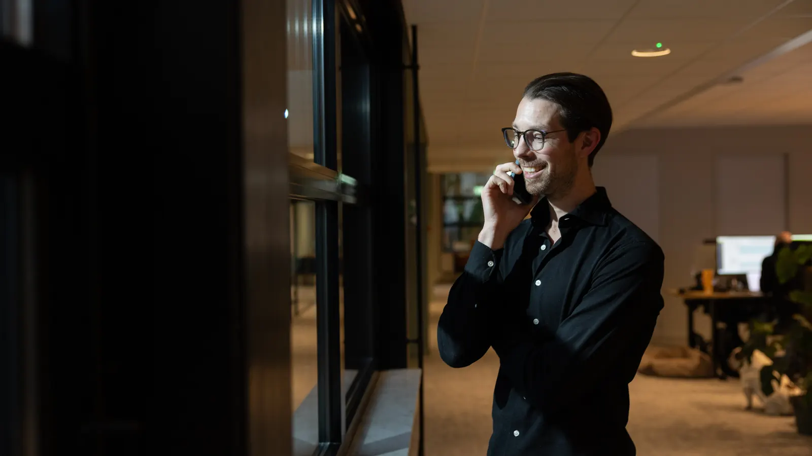 Een collega belt staand bij het raam