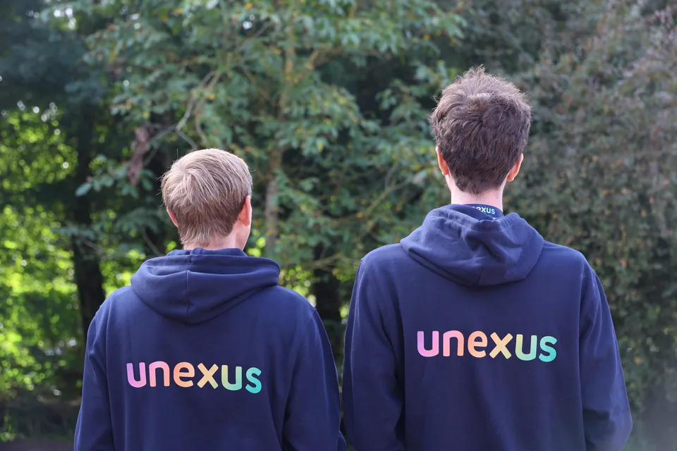 Twee collega&rsquo;s van achteren, met het nieuwe Unexus-logo op hun hoodie