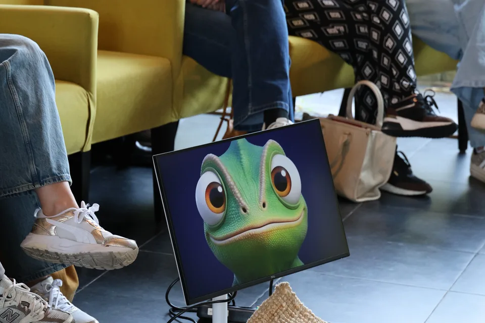 Nex, de kameleon van Unexus, op een scherm naast de stoelen in de zaal