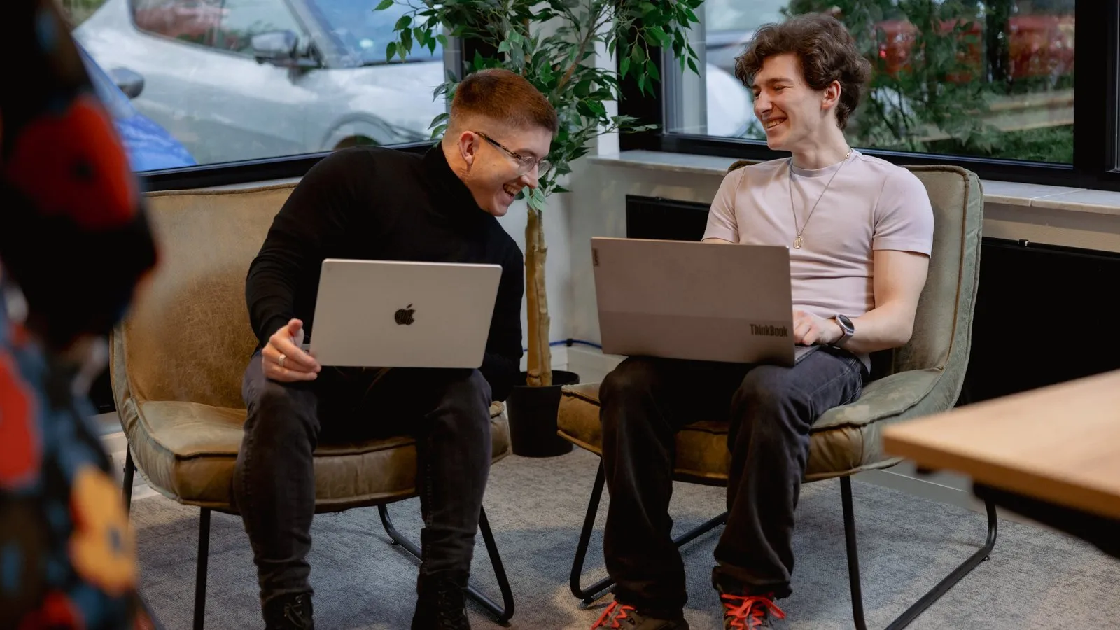 Twee collega&rsquo;s van Unexus met laptops in de zithoek